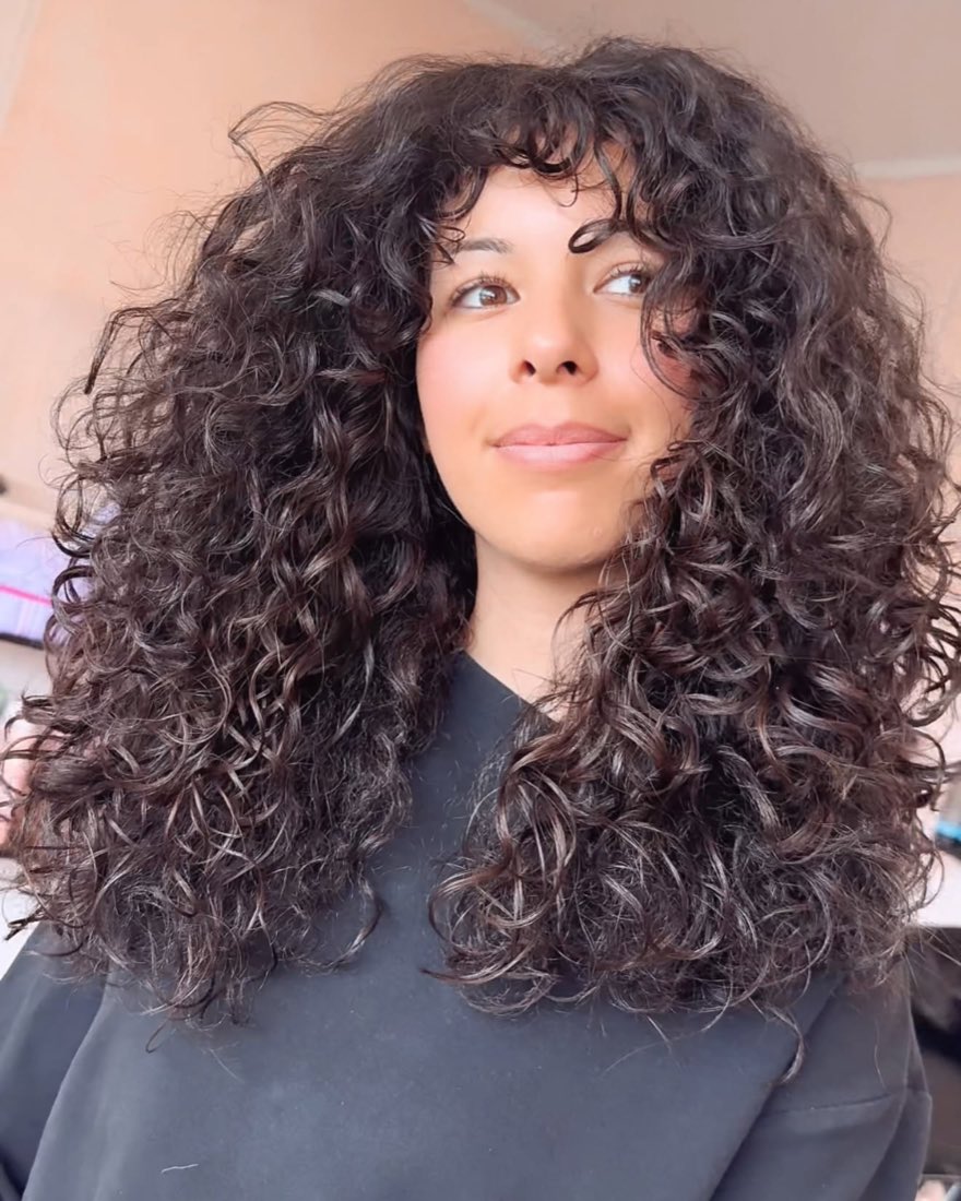 Long layered curls falling past the shoulders, shaped to their natural pattern
